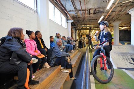 Woman speaking to people on bleachers at Mike's Bike Park