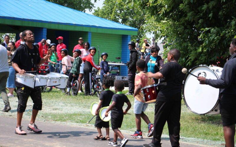 Marching band at Dayton Bike Yard Grand Opening event while cyclists around shelter watch.